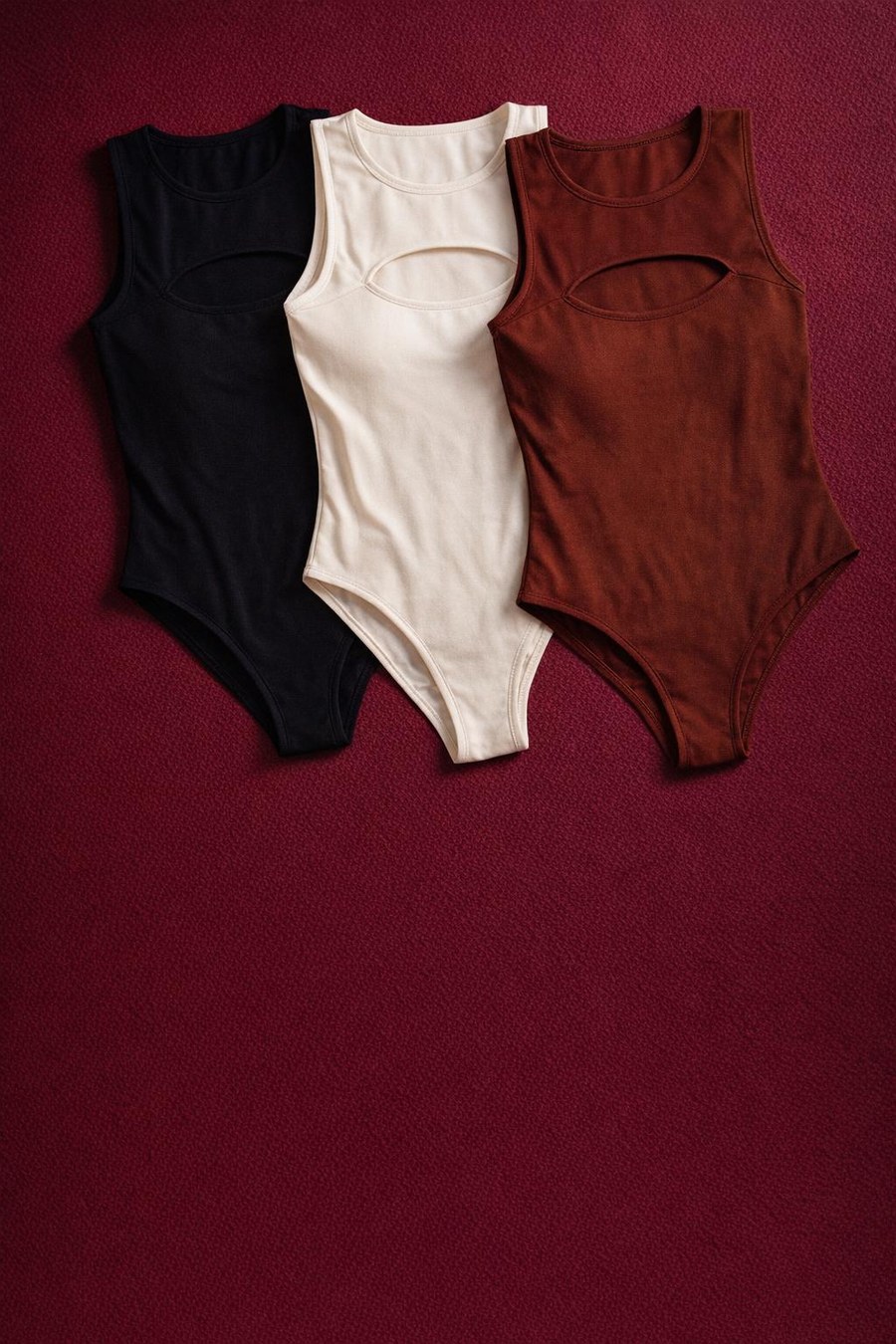 Três bodys dobrados nas cores preto, off-white e marrom café